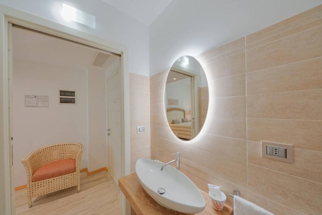 A bathroom with a white sink, a mirror, and a wicker chair.