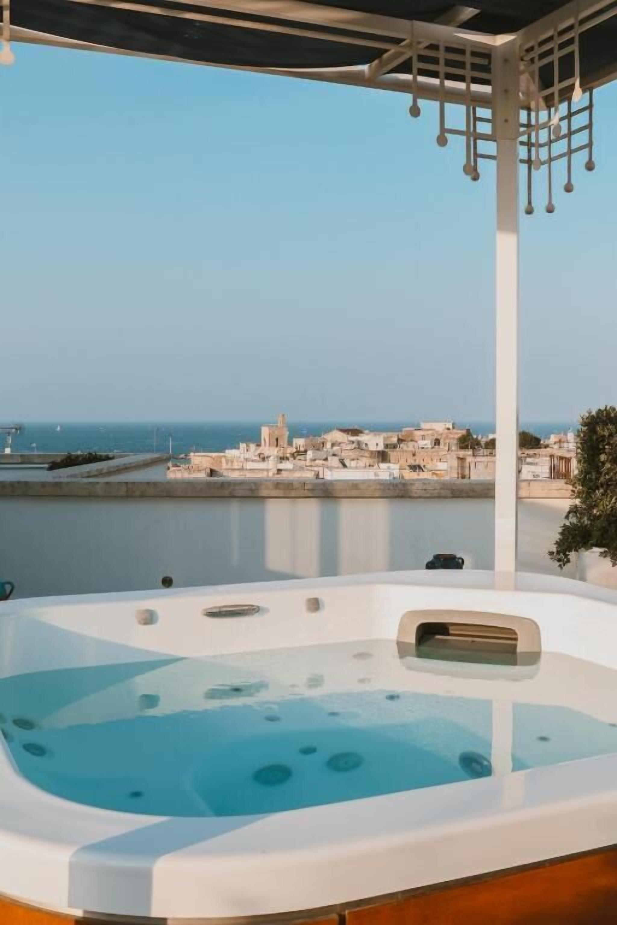 A hot tub with a clear view of a coastal town and the sea in the background.