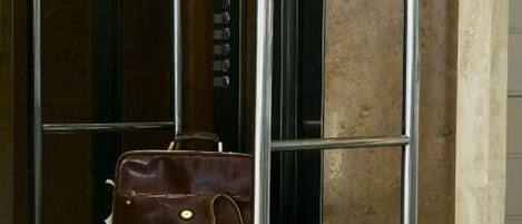 A luggage cart with two leather bags inside an elevator.