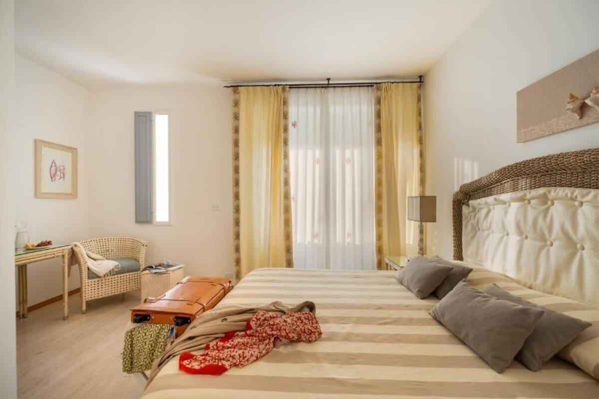 A hotel room with a bed, a chair, a table, and a suitcase.