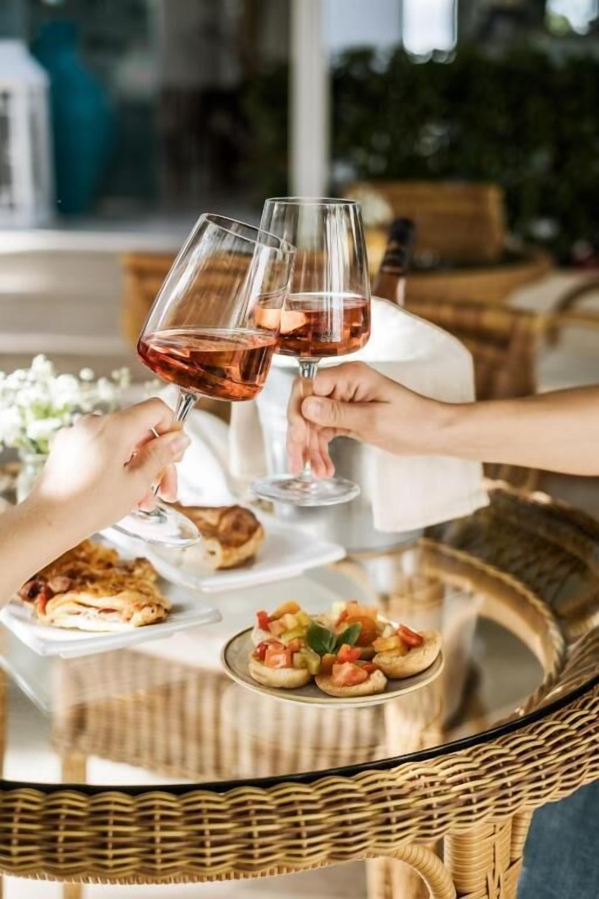 Une table ronde en verre, dotée d’un piétement en osier, entourée de chaises en osier.