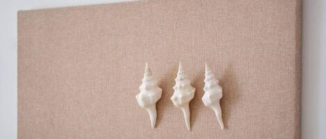 Pared beige con textura y tres adornos blancos con forma de concha.