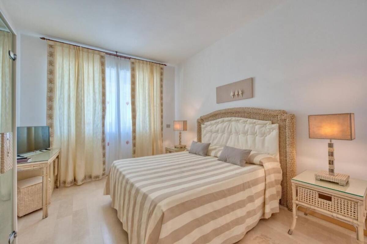 A hotel room with a bed, a desk, a television, and a lamp.