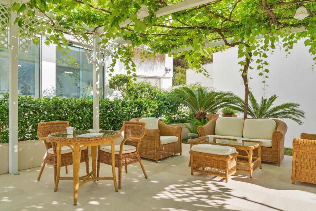 An outdoor patio area with wicker furniture, including a table and chairs, and a sofa.