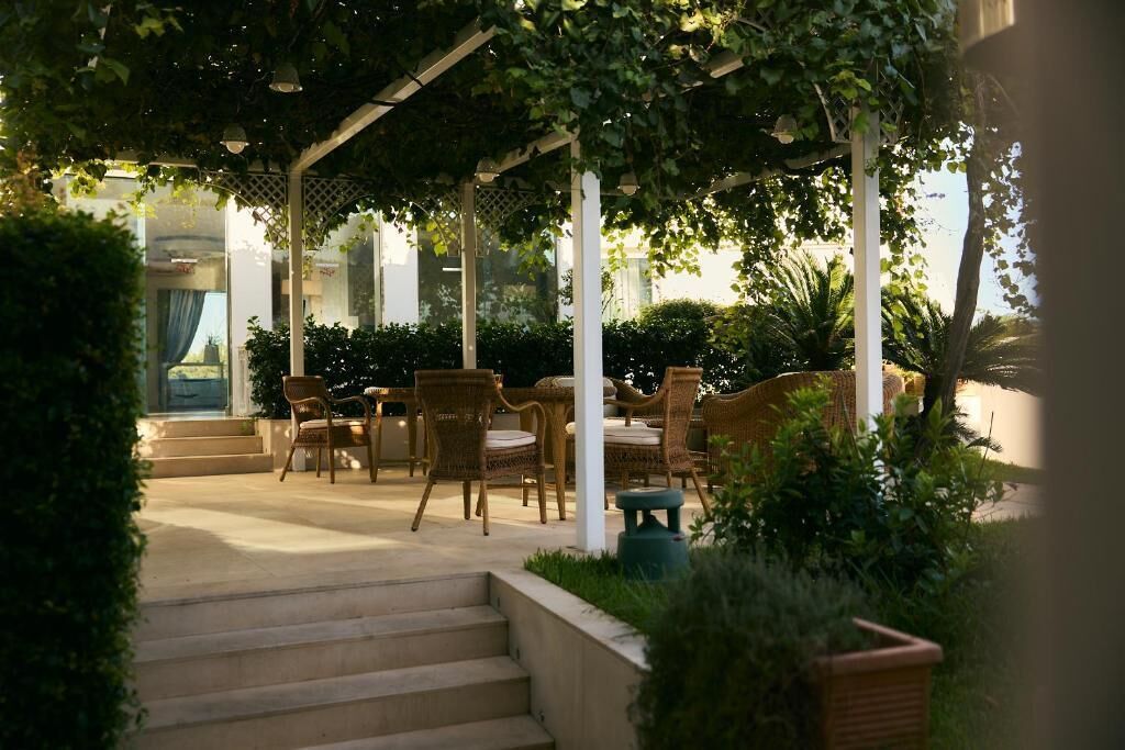A covered outdoor seating area with wicker furniture and a pergola structure.