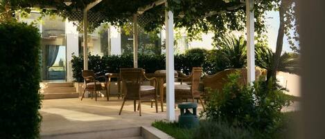 A covered outdoor seating area with wicker furniture and a pergola structure.