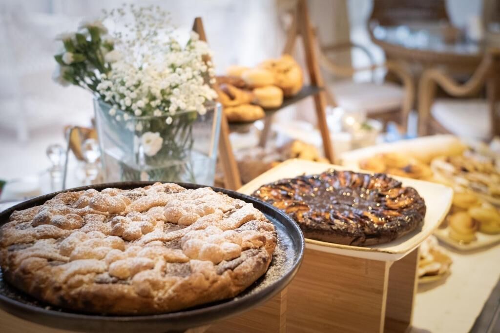 A dessert display with a variety of pastries and a pie, including a dusted cake and a tart.