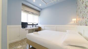 Un dormitorio con cama, un escritorio con computadora y una ventana con persianas.