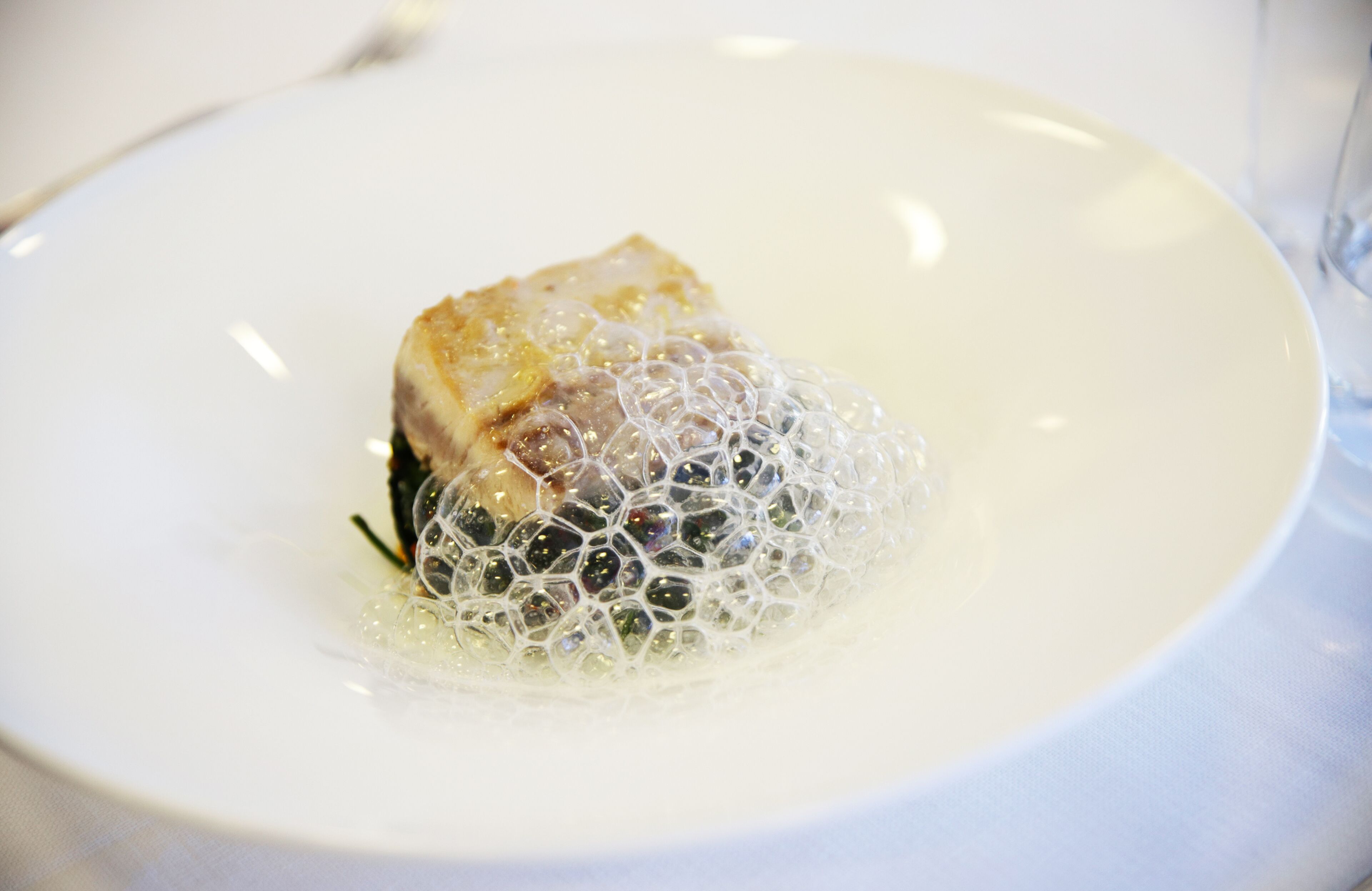 Une assiette blanche avec un morceau de nourriture et une structure en forme de bulle.