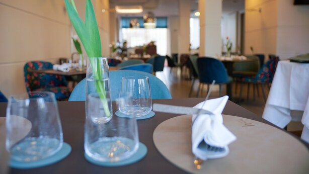 A dining table with a vase of flowers, two empty glasses, and a napkin. - Hotel Palace (Battipaglia)