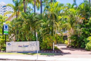 A sign for Mari Court Resort with palm trees and a building in the background. - Mari Court Resort (Surfers Paradise)