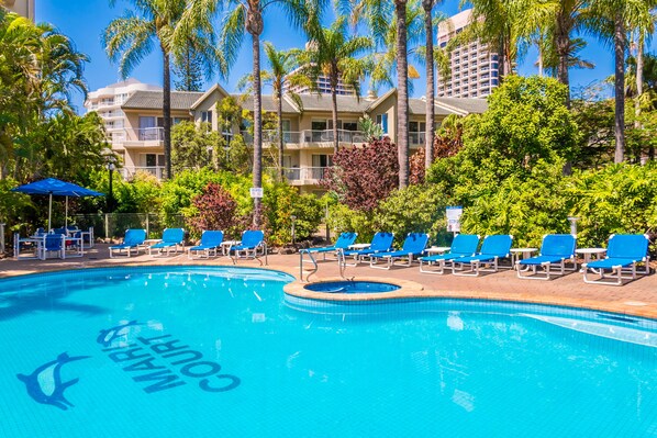 A swimming pool with lounge chairs and palm trees. - Mari Court Resort (Surfers Paradise)