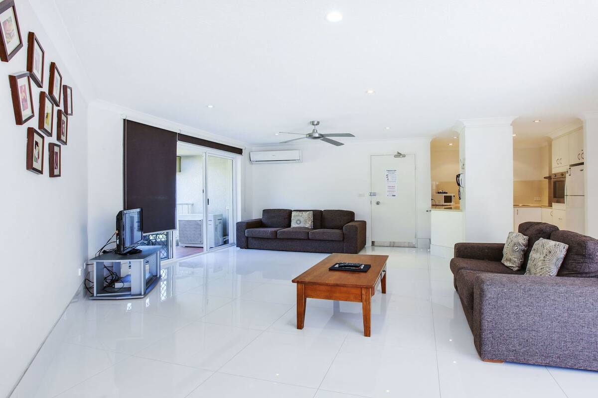 A modern living room with two sofas, a coffee table, a TV, and a ceiling fan.