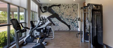 Un gimnasio con cintas de correr, bicicletas estáticas y máquinas de pesas.