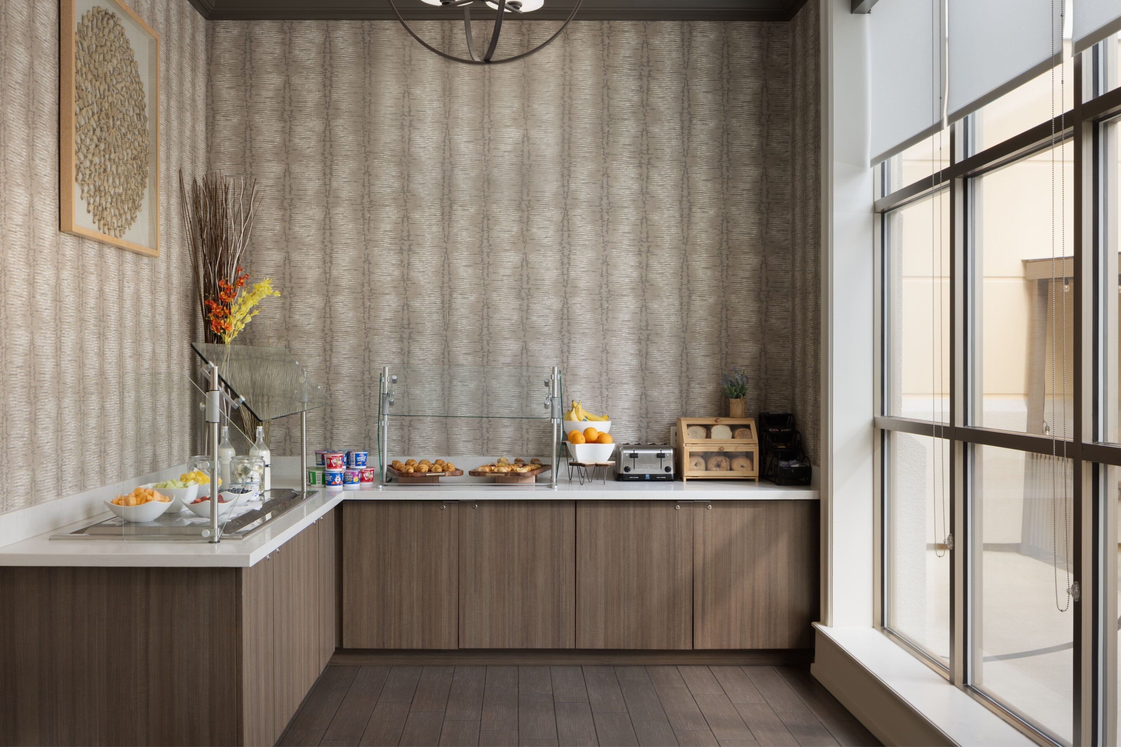 Une cuisine moderne dotée d’un îlot central intégré, d’une grande fenêtre et d’un élément décoratif mural.