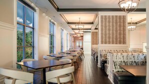 Un restaurant doté de longues tables communes et de banquettes, de grandes fenêtres et de luminaires suspendus.