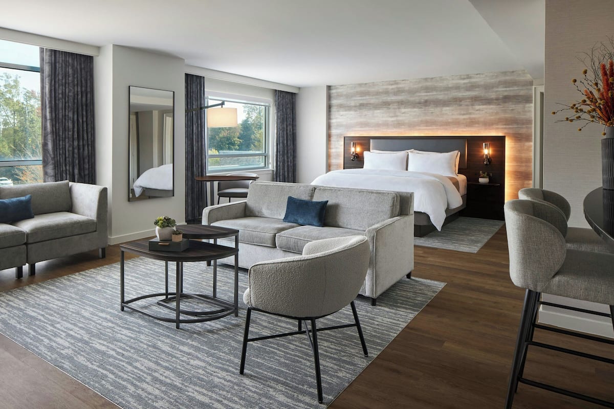 Ein modernes Hotelzimmer mit einem großen Bett, einer Couch, einem kleinen Tisch und einem Sessel.