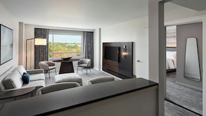 A hotel room with a dining area, a TV, and a view of the outdoors.