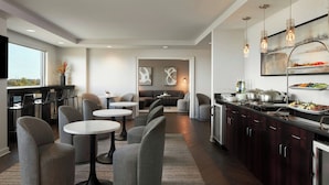 A modern kitchen with a buffet setup, seating area, and artwork on the walls.