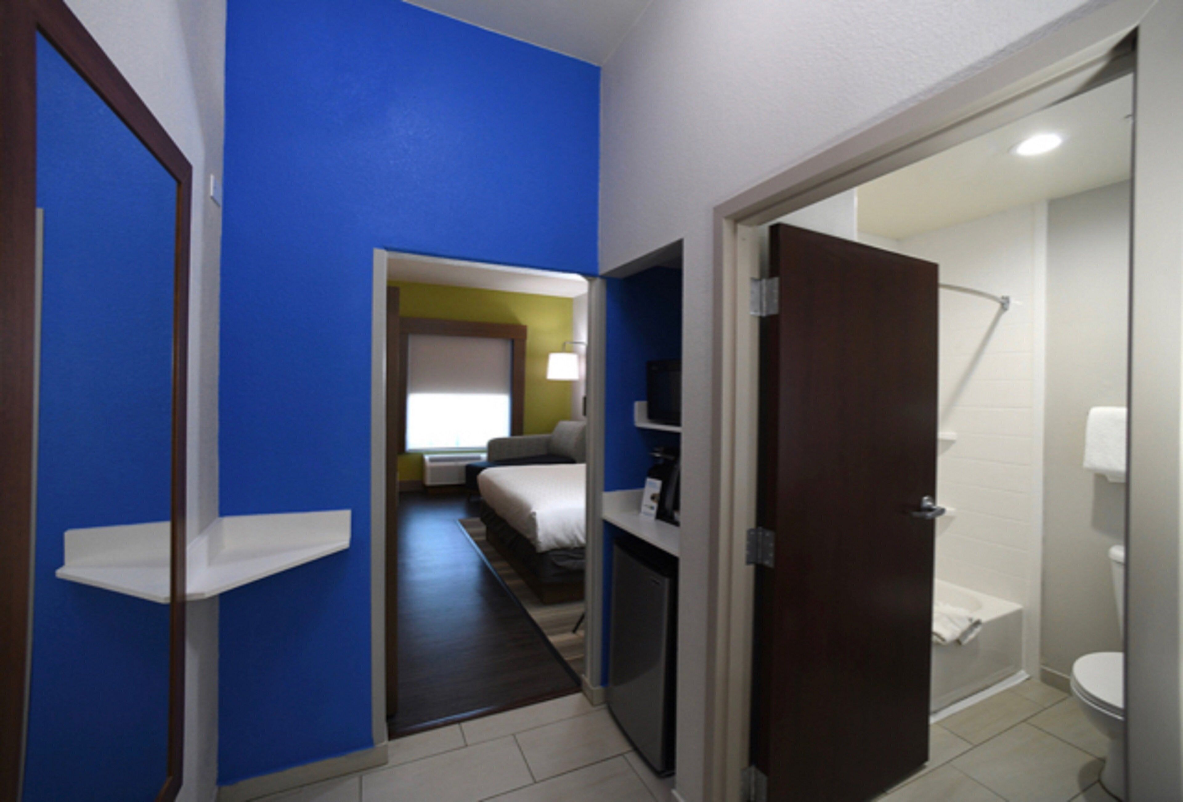 Une chambre d’hôtel comprenant un lit, un bureau, une chaise, une télévision et une salle de bain avec des toilettes et une douche.