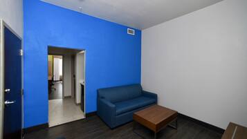 A room with a blue wall, a wooden coffee table, a blue sofa, and a door leading to another room.