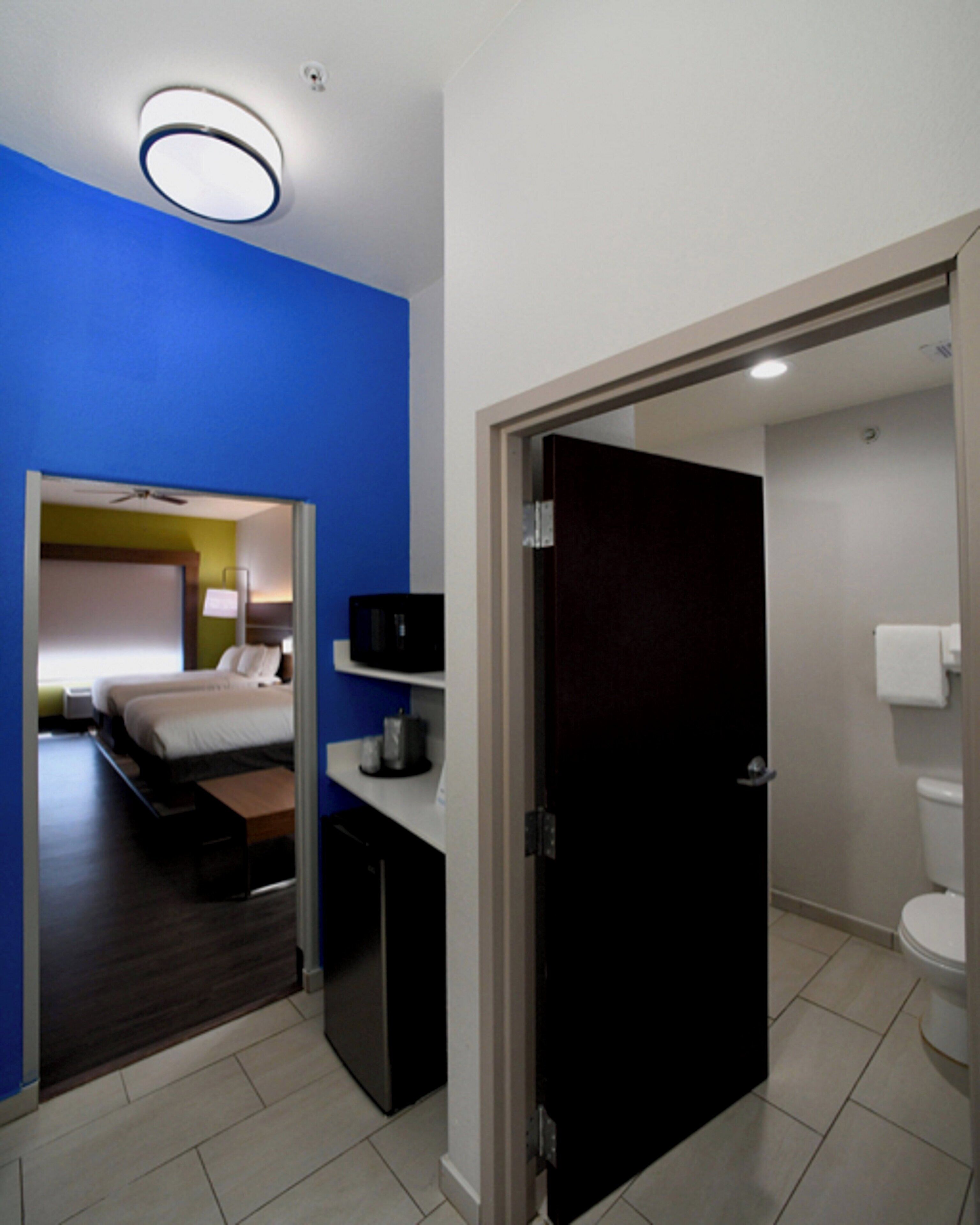 A hotel room with a bed, bedside table, and a bathroom with a toilet and sink.