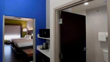 Ein Hotelzimmer mit Bett, Nachttisch und einem Badezimmer mit Toilette und Waschbecken.