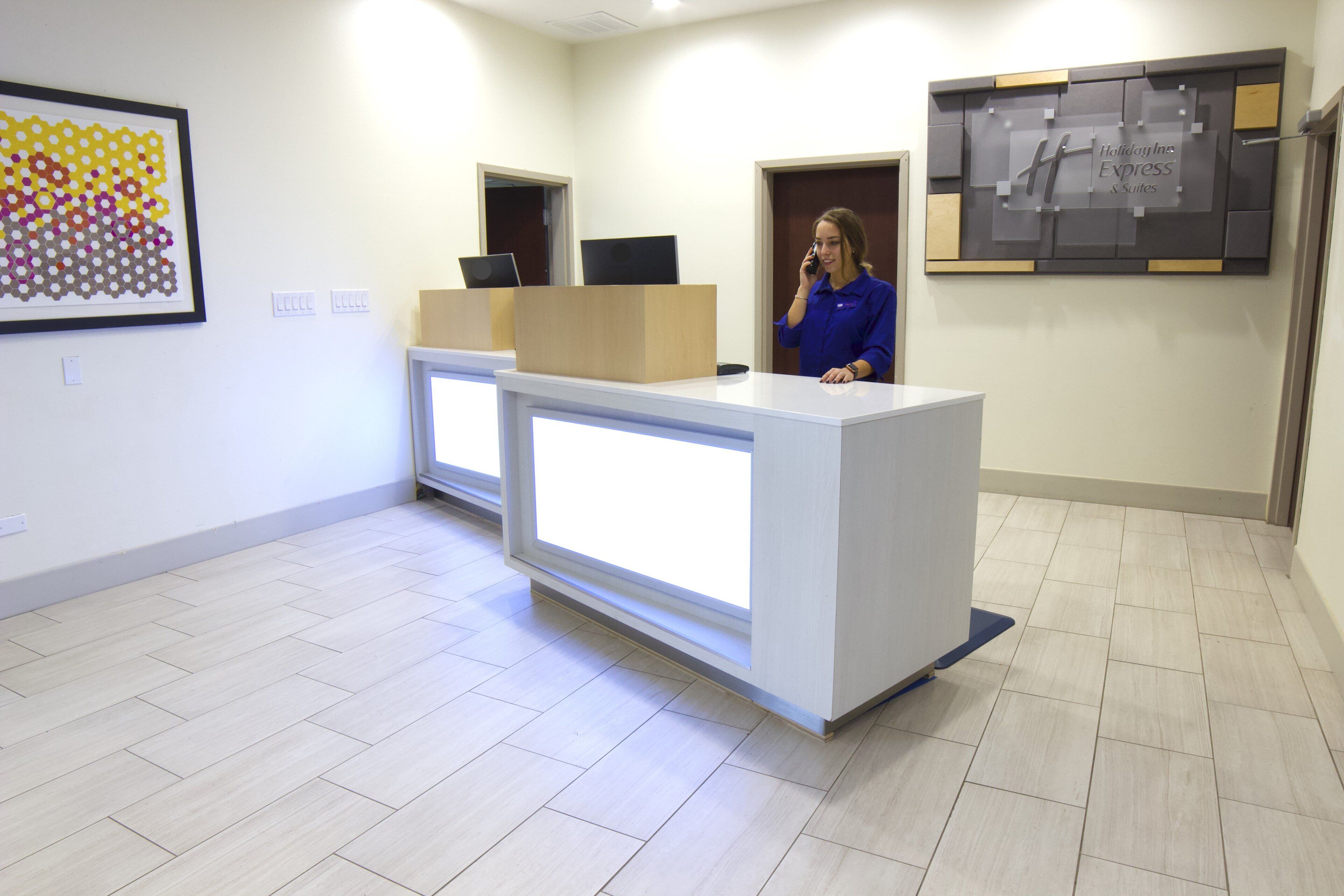 A reception desk with a computer, a framed artwork, and a sign for Holiday Inn Express Suites.