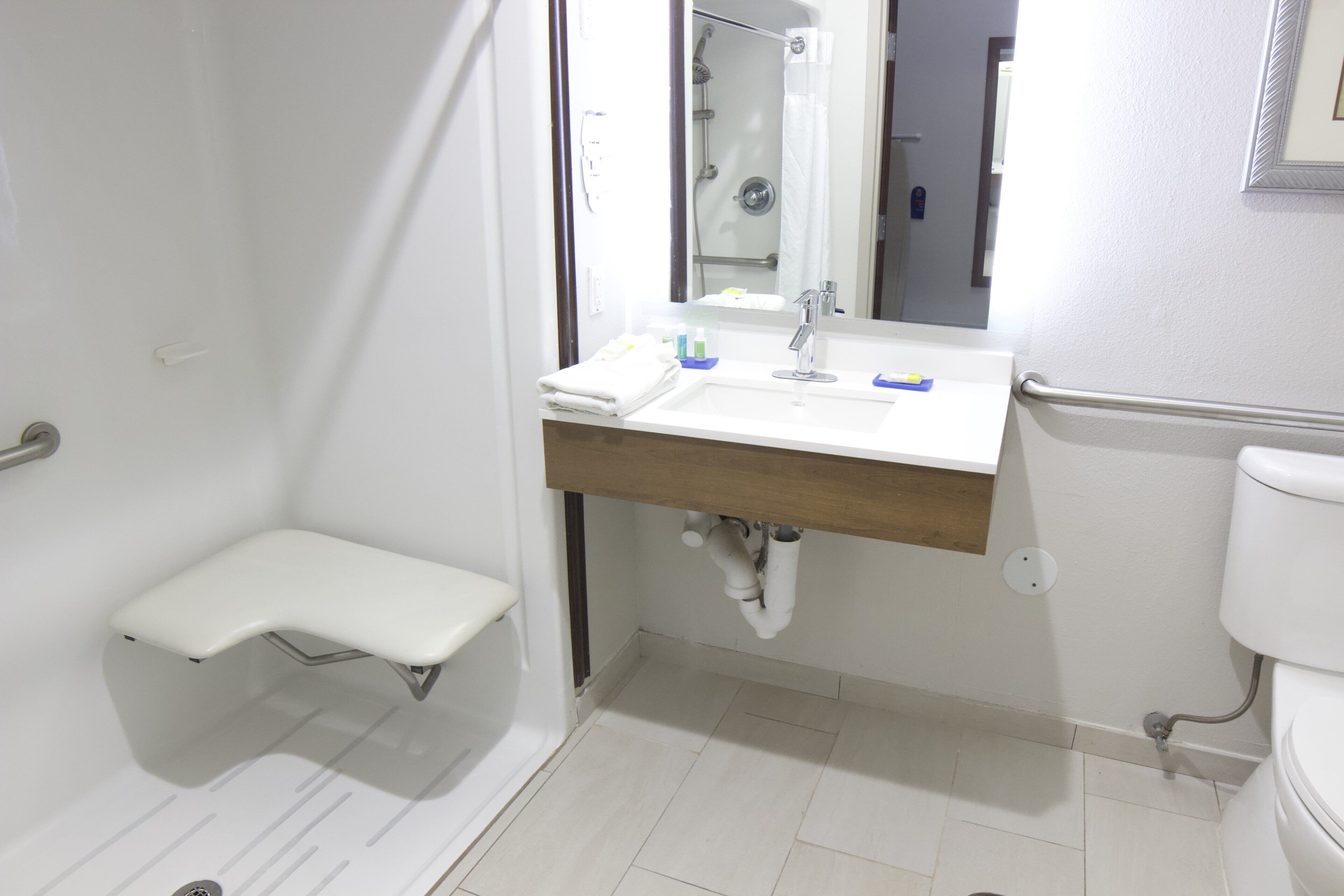 A bathroom with a shower, a sink with a mirror, and a toilet.