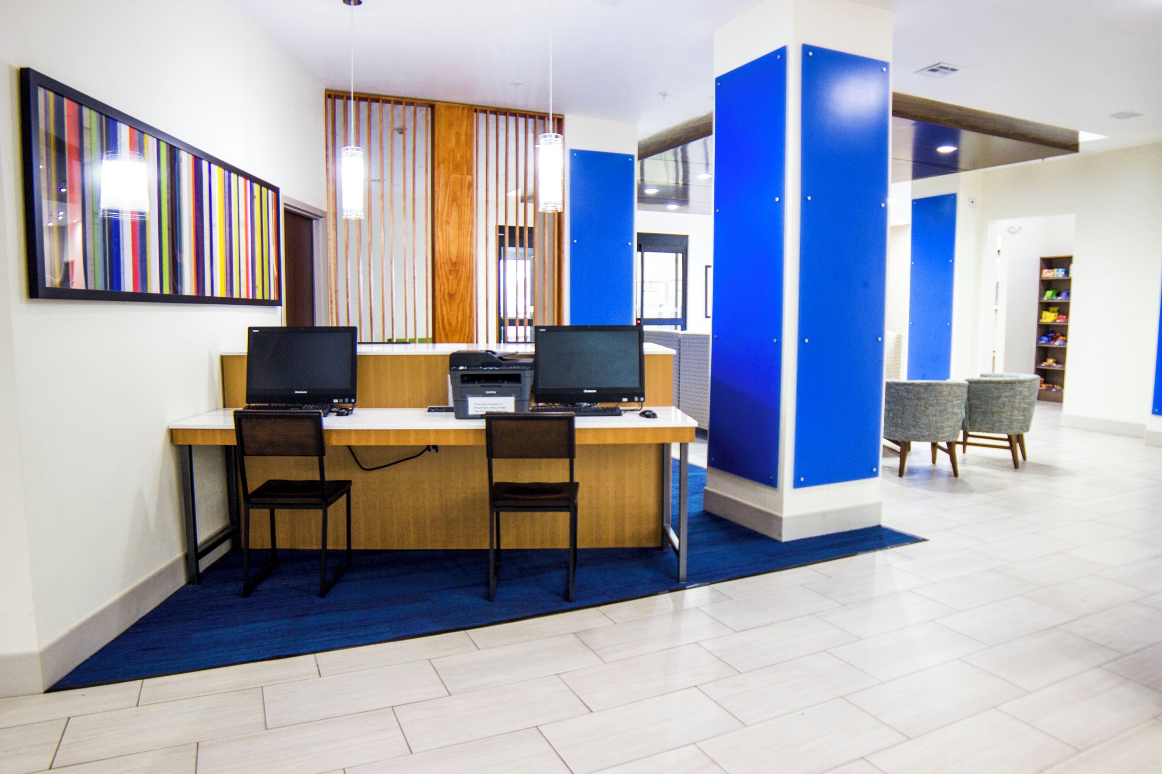 A modern office space with two desks, computers, and chairs.