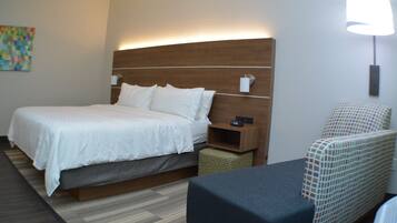 A hotel room with a large bed, bedside table, and a chair.