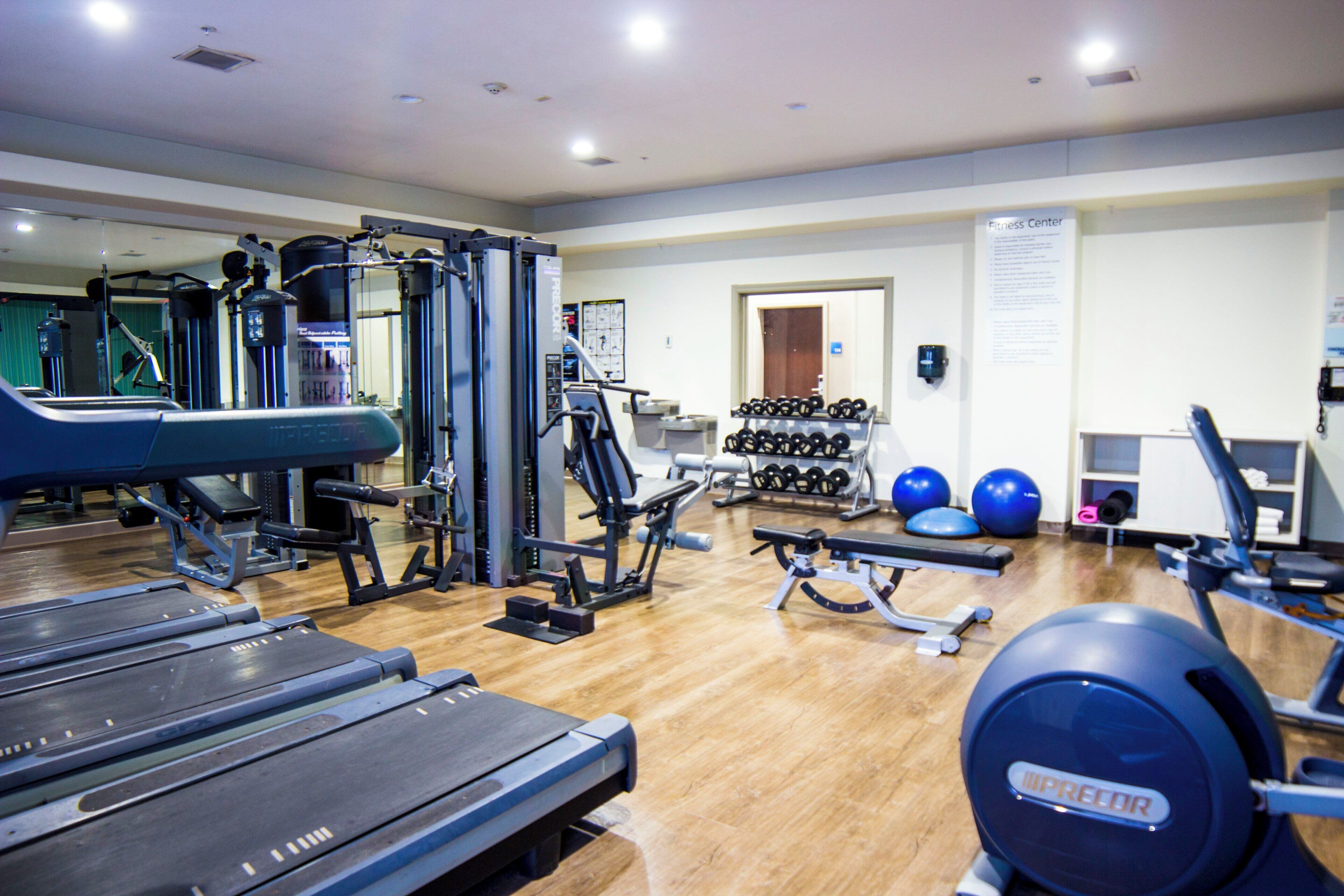 Un gimnasio con diversos equipos de ejercicio, incluyendo cintas de correr, máquinas de pesas y pesas libres.