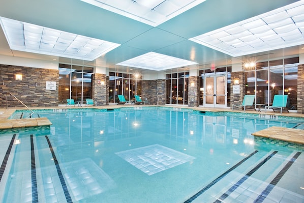 An indoor swimming pool with clear lanes, a stone wall, and a glass entrance.
