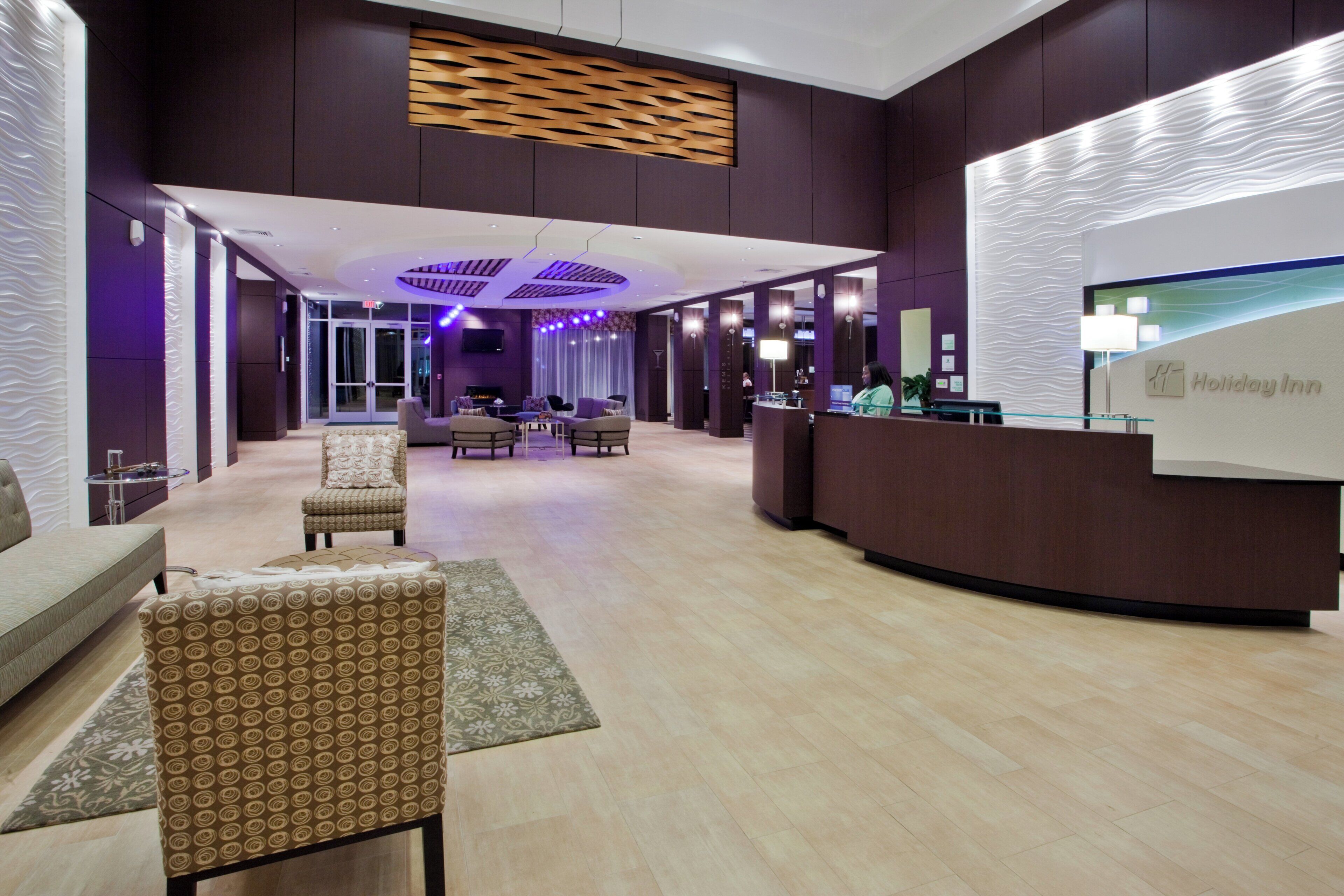 A hotel lobby with a reception desk, seating area, and a large window.