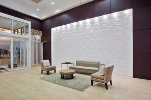 A modern living room with a sofa, two armchairs, a coffee table, and a patterned rug.