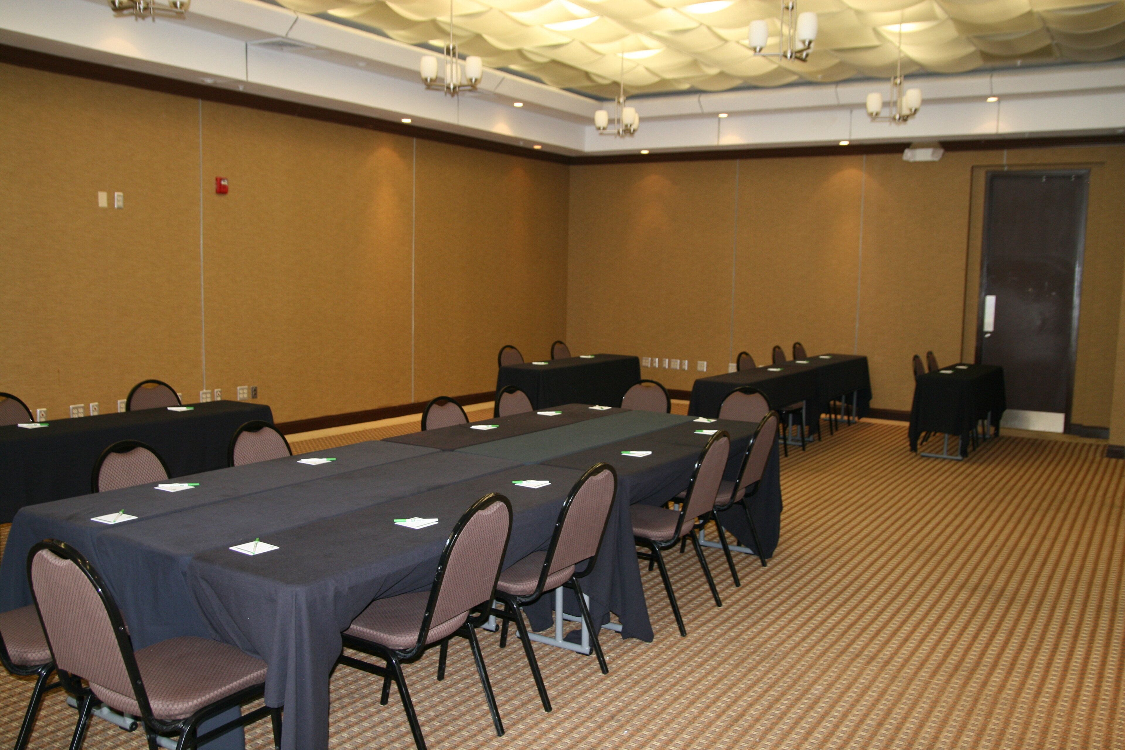 Un salón de conferencias con una mesa larga, varias sillas y piso alfombrado.