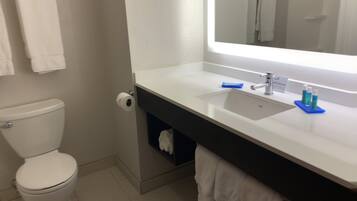 A bathroom with a toilet, sink, mirror, and towel rack.