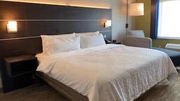 Een hotelkamer met een groot bed, nachtkastjes, een stoel en een wandlamp.