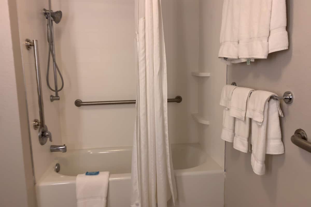A bathroom with a bathtub, shower, and towel rack.