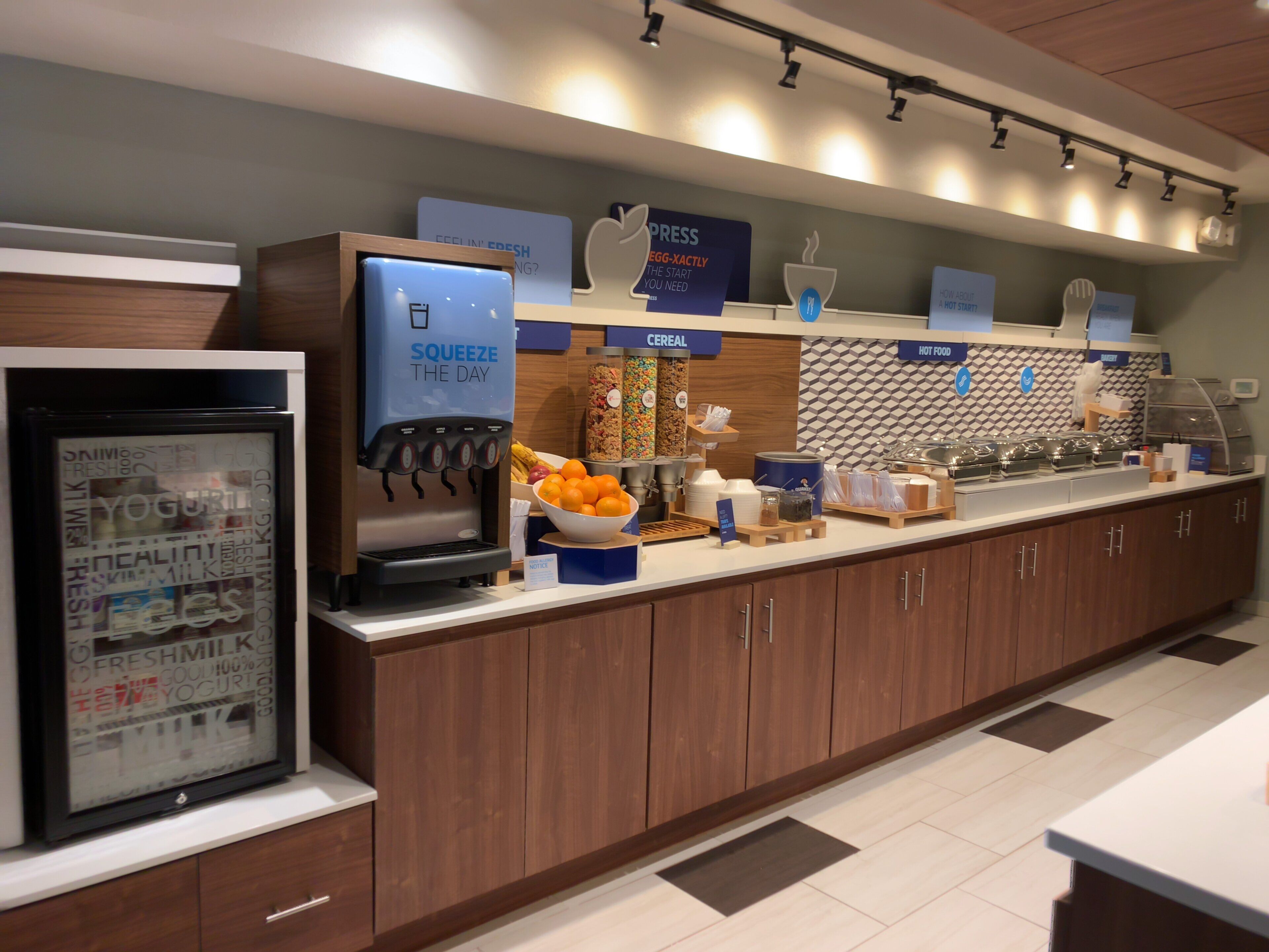 Una barra de desayuno con dispensador de yogur, cereales y estación de alimentos calientes.