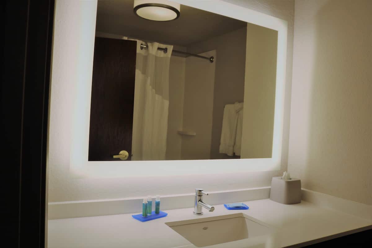A bathroom with a large mirror, a sink, and a towel rack.