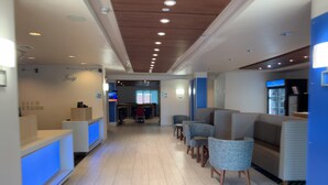 A modern hotel lobby with a reception desk, seating area, and a counter with a beverage dispenser. - Holiday Inn Express & Suites Exmore - Eastern Shore by IHG (Exmore)
