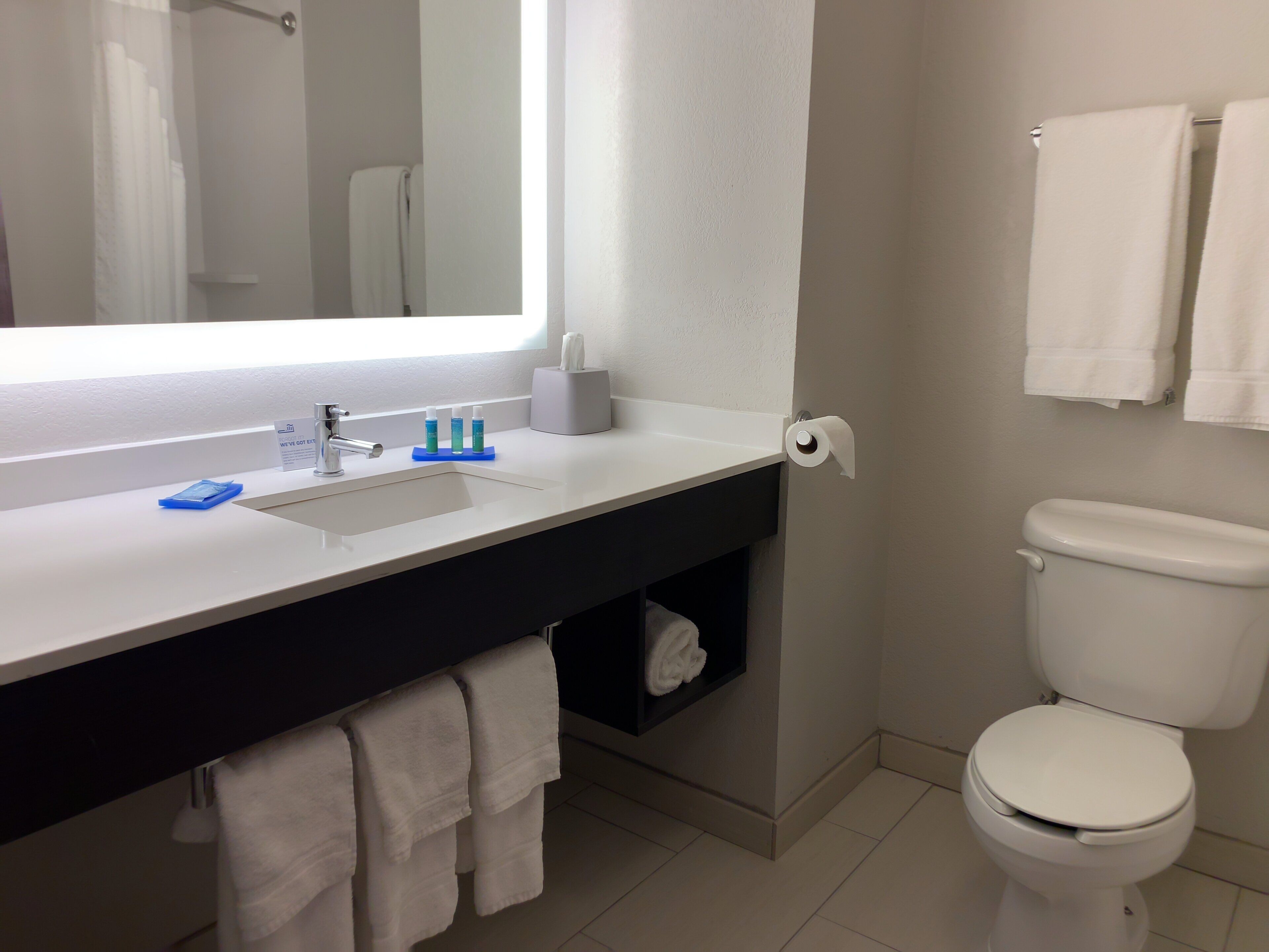 A bathroom with a white sink, a mirror, a toilet, and a towel rack.