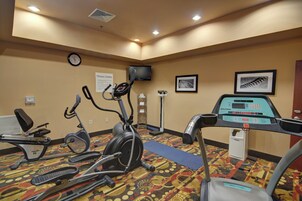 A fitness center with exercise equipment, a clock, and informational signs.