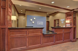 A reception desk with a marble back wall, a check-in counter, and a reception area with a patterned wall. - Holiday Inn Express & Suites Altus by IHG (Altus)
