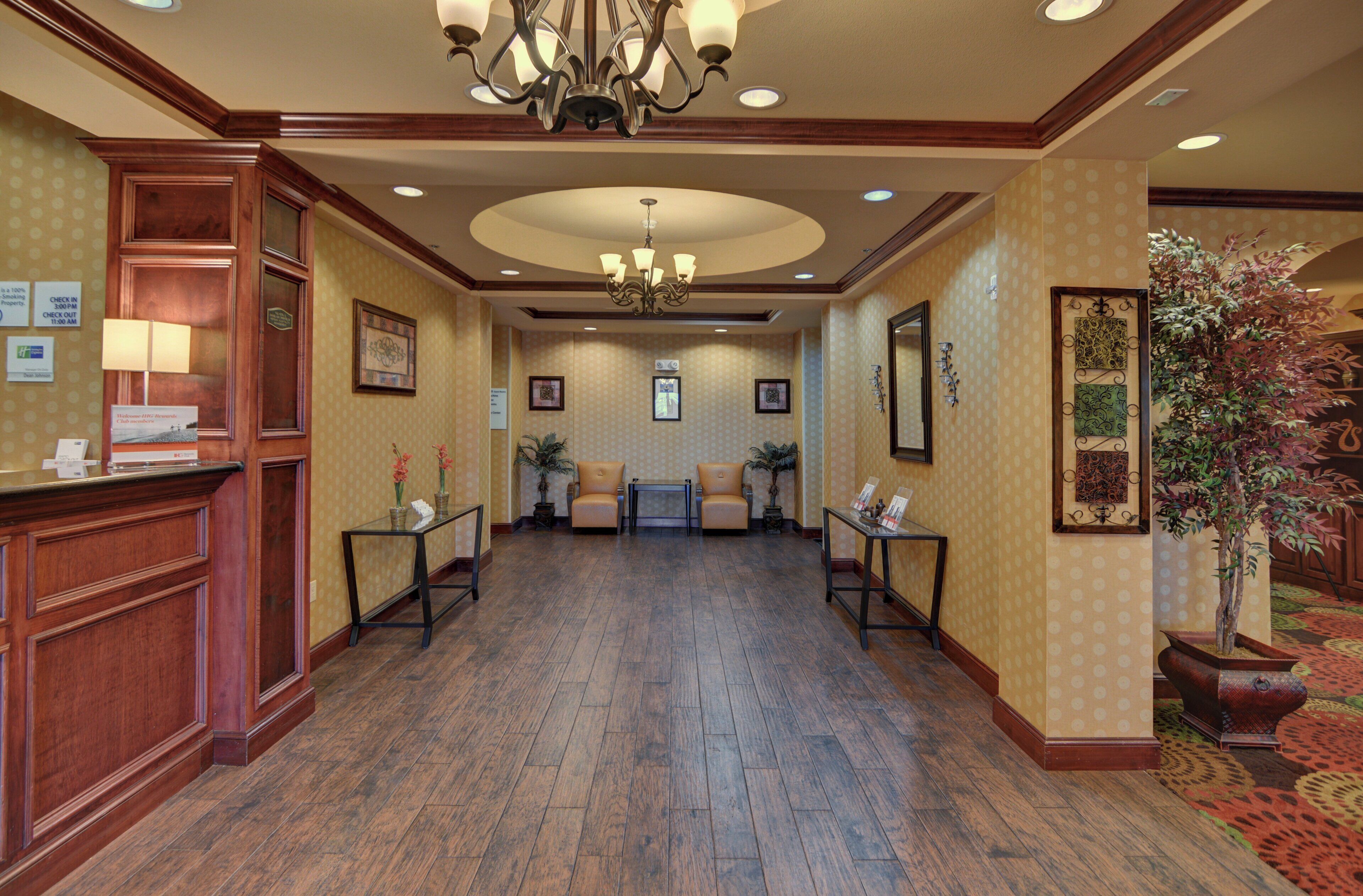 A hotel lobby with a reception desk, seating area, and a chandelier.