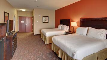 A hotel room with two beds, a dresser, a television, and a lamp.