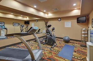 A fitness center with exercise equipment, a clock, and a water dispenser.
