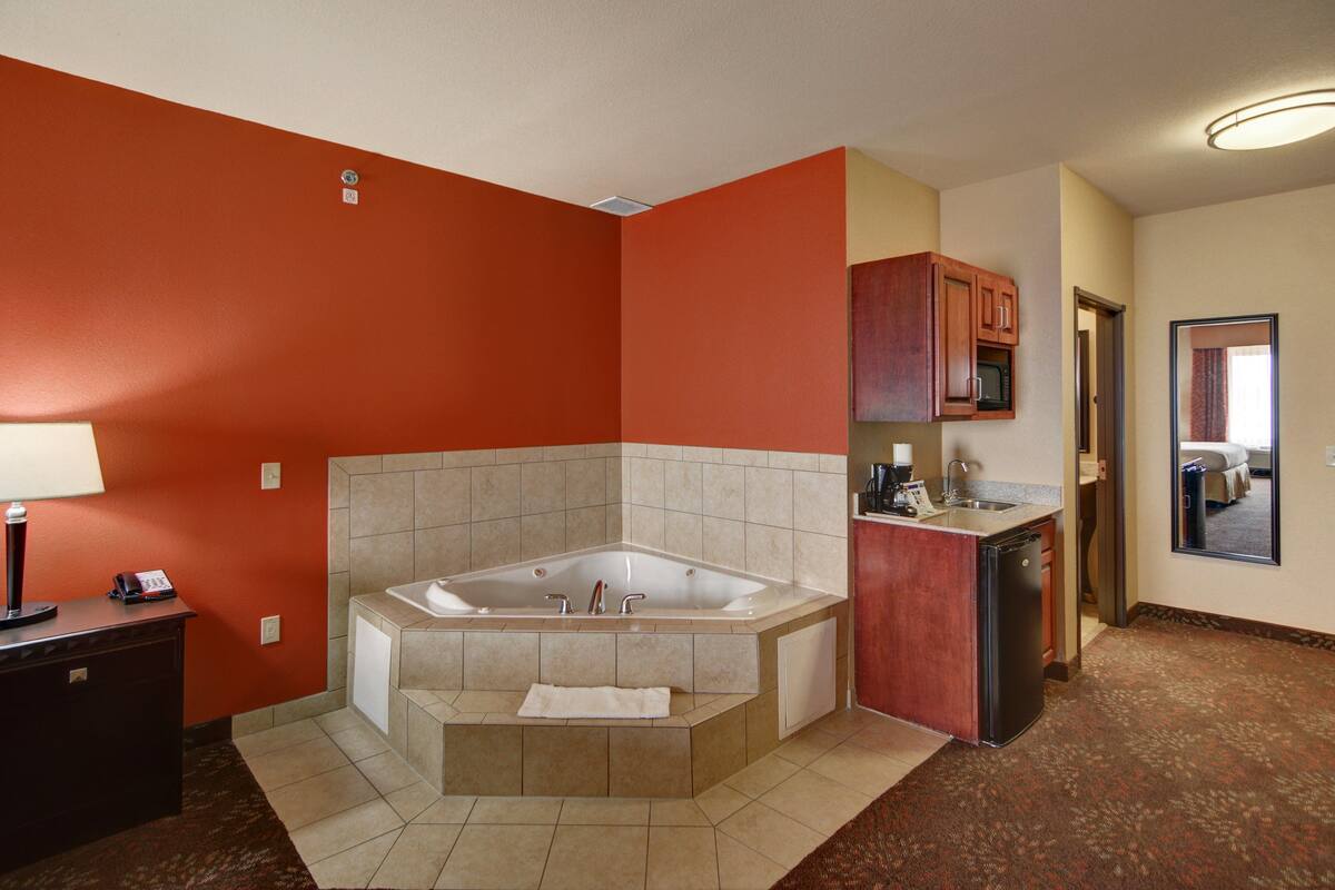 Un baño con una bañera grande, un lavamanos y un tocador con espejo.