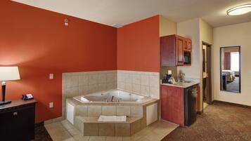A bathroom with a large bathtub, a sink, and a microwave in a cabinet.